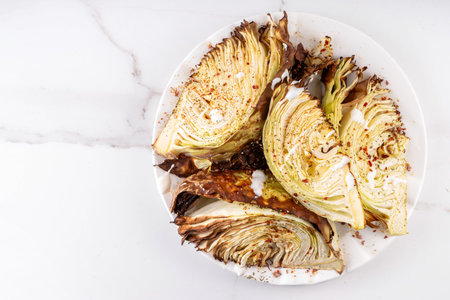 Roasted baked cabbage with cheese and aromatic herbs, vegetarian healthy diet food recipe with creamy sauce and spices on kitchen table backgroundの写真素材