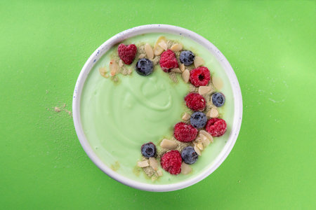 Green matcha yogurt bowl with fresh berries, nuts and granola. Tasty healthy smoothie bowl for healthy breakfastの写真素材