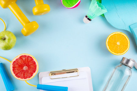 Fitness and healthy food lifestyle concept. Dumbbells, healthy full of vitamins fruits -apple, grapefruit, orange, with water bottle, jump rope on colorful bright background, top view copy spaceの写真素材