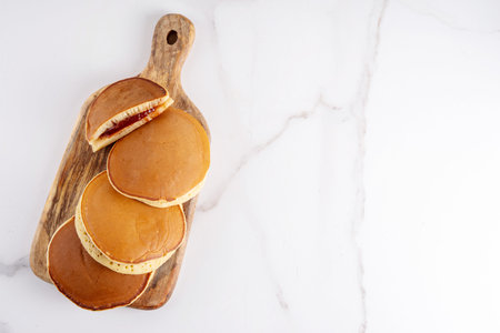 Dorayaki, classic Japanese pastry, golden honey pancake sandwich filled with sweet red bean paste or...