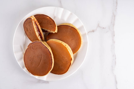 Dorayaki, classic Japanese pastry, golden honey pancake sandwich filled with sweet red bean paste or...