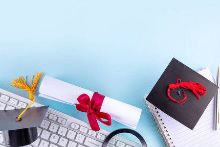 Happy graduation day background. Graduation themed accessories - rolled diploma with red ribbon, graduation cap, books and notebook for preparing for exams, keyboard, eyeglasses and pen