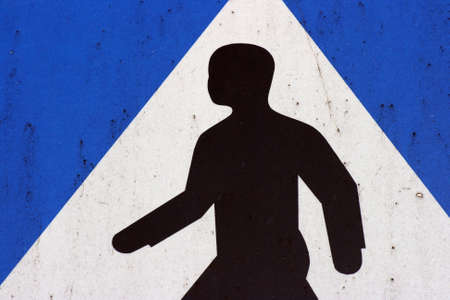 A crosswalk sign in blue, white and black