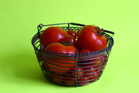 A metallwiring bowl filled with tomatoes in different sizesの写真素材