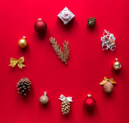 on a red background a layout of Christmas ornaments gift bows of nuts and cones in the form of hours that are thrown 12 new year arrow Christmas tree branches conceptの写真素材