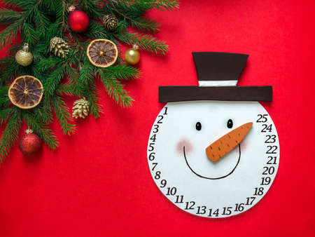 on a red background a layout in a corner of fir branches and Christmas ornaments and in the center lies the head of a snowman adventの写真素材
