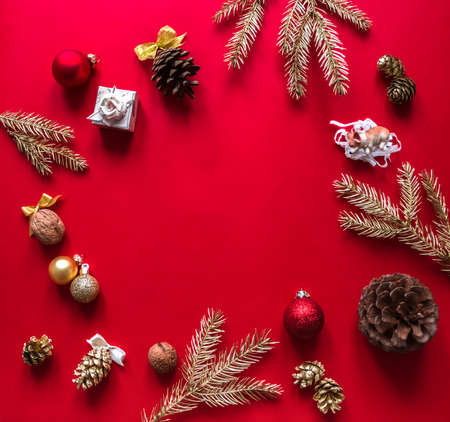 On a red raspberry background, the Christmas and New Year decorations and gilded branches of the Christmas tree are arranged in a circleの写真素材