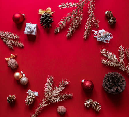 On a red raspberry background, the Christmas and New Year decorations and gilded branches of the Christmas tree are arranged in a circleの写真素材