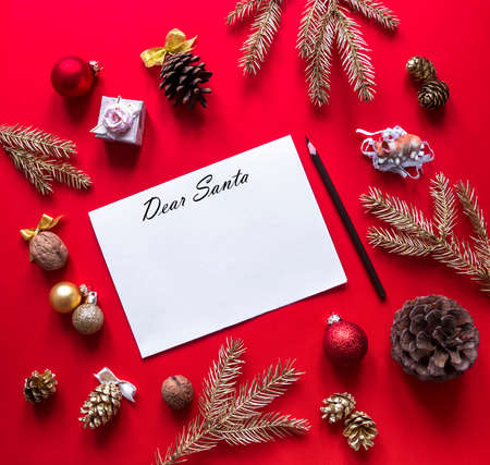 on a red raspberry background, New Year and Christmas decorations and spruce gold branches are arranged in a circle, and in the center lies a white sheet with a letter to Santa Claus and a pencilの写真素材