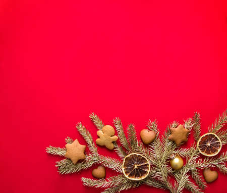 on a red background of gold spruce branches decorated with gingerbread spices oranges and ballsの写真素材