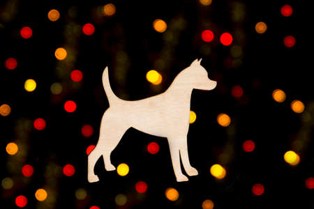 wooden decoration in the form of a dog silhouette on a background of yellow and red bokeh lights on a black backgroundの写真素材