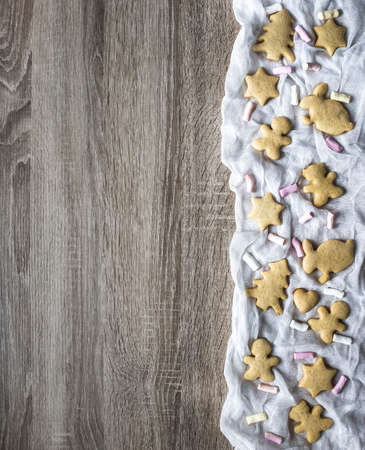 a wooden table, and on the right are laid out on white cloth gingerbread cakes as a tree of hearts of hares of little teddy bears and stars, marshmallows layの写真素材