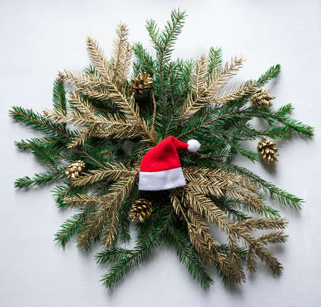 on a wreath of fir branches and cones of gold color is the cap of Santa Claus new yearの写真素材