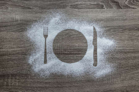 on a wooden background with powdered powder snow covered with silhouette plate fork knife appliancesの写真素材