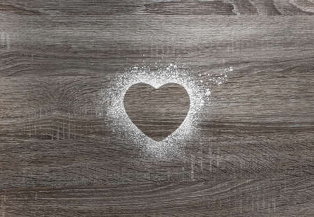 on a wooden background with powdered powder snow a silhouette of the heartの写真素材
