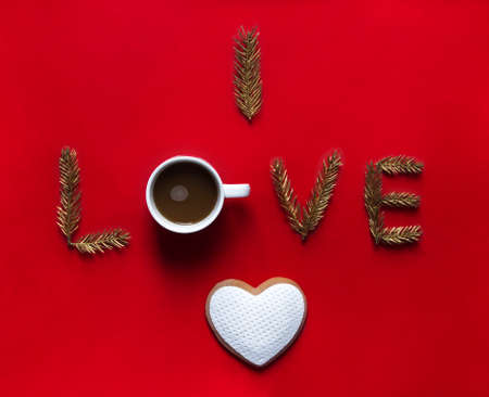 on a red background the word love instead of letters about a mug with coffee down a cookie in the form of a heartの写真素材