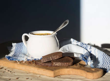 on the table a blue napkin with ornament pattern and soup tureen with yellow soup in the sun bread wooden board seedsの写真素材