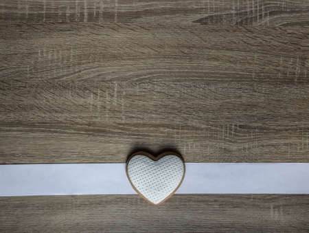 on a wooden background a white stripe and cookies in the form of a heartの写真素材