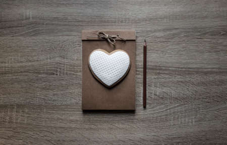 on a wooden background lies a craft notepaper scrapbooking on it cookie heart pencil brownの写真素材