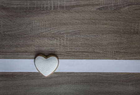 on a wooden background a white stripe and cookies in the form of a heartの写真素材