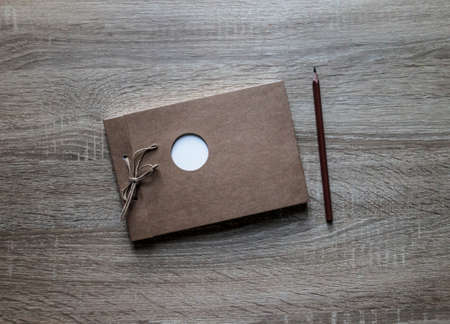 on a wooden background lies a craft notepad scrapbooking pencil on a notepad white circle frameの写真素材