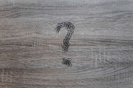 on a wooden background is a paper clip with a question markの写真素材