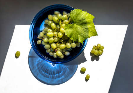 Green grapes in a blue glass vase in the sun view from aboveの写真素材