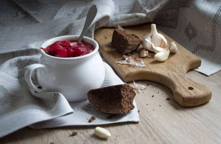 On the table a blue napkin with ornament pattern and soup tureen with red beet soup on the sun bread garlicの写真素材