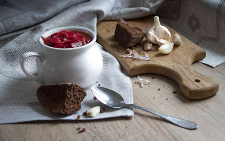 on the table a blue napkin with ornament pattern and soup tureen with red beet soup on the sun bread garlicの写真素材
