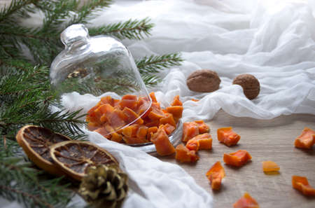 dried fruit pumpkin pineapple orange candied fruits on a table under a glass cap cap christmas tree cones nuts cloth nutsの写真素材