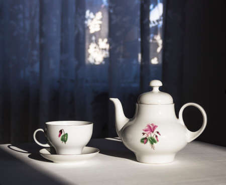 On the table a kettle and a cup in the sunbeamの写真素材