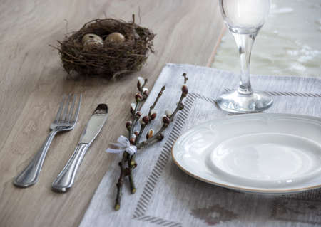 on the table a napkin with a plate a fork glass a knife and willow branchesの写真素材