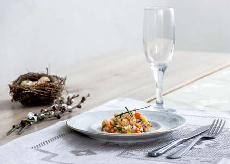 On a table a napkin with a plate of vegetable stew a glass of fork and a branch of a willow's nest with quail eggsの写真素材