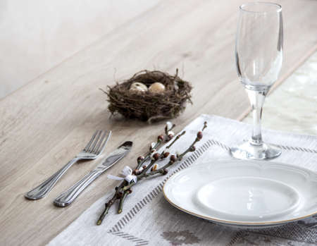 On the table a napkin with a plate of a glass fork and a branch of a willow's nest with quail eggsの写真素材