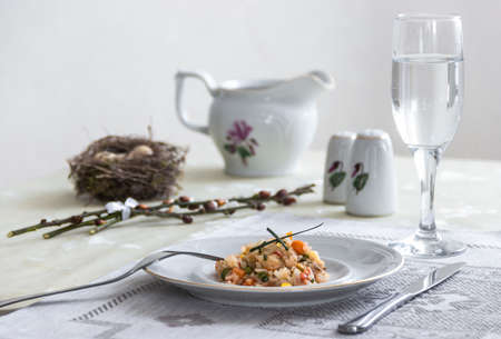 on the table napkin with a plate vegetable stew green onion glass fork knife and willow branches with quail eggs salt pepper sauceの写真素材