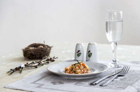 on a table napkin with a plate vegetable stew green onion glass fork knife and willow branches with a quail eggs salt pepperの写真素材