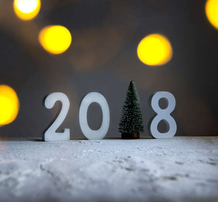on the snow-covered field there are numbers 2018 instead of one-piece fir-tree lights bokeh glowの写真素材