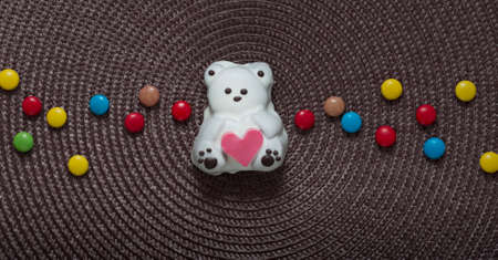 on a napkin in the center of a cake like a bear with a heart in his hands next to a candy coloredの写真素材