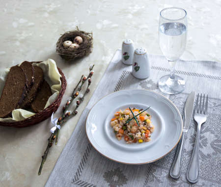 on a table napkin with a plate vegetable stew green onion glass fork knife and willow branches with a quail eggs salt pepper breadの写真素材