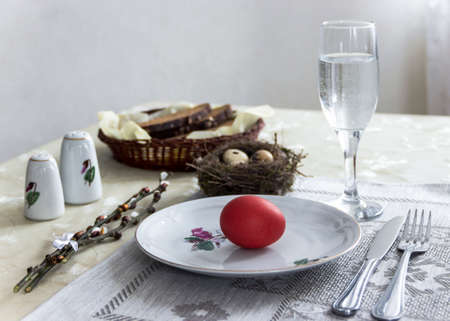 on a plate egg red color fork knife glass of water bread pepper salt nest easter