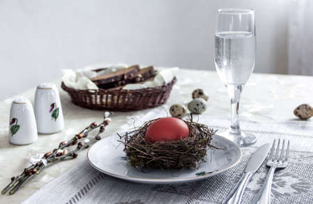 on a plate egg red color fork knife glass of water bread pepper salt nest easterの写真素材