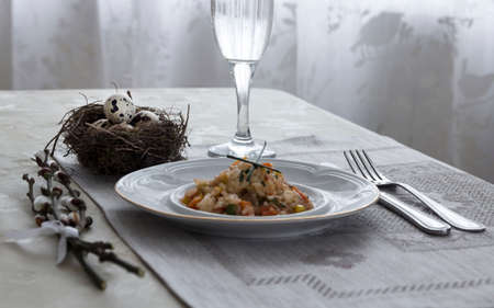 on a table napkin with a plate vegetable stew green onion glass fork knife and willow branches with a quail eggs salt pepperの写真素材