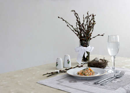 on a table napkin with a plate vegetable stew green onion glass fork knife and willow branches with a quail eggs salt pepperの写真素材