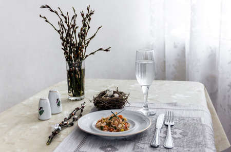 on a table napkin with a plate vegetable stew green onion glass fork knife and willow branches with a quail eggs salt pepperの写真素材