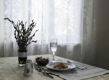 on a table napkin with a plate vegetable stew green onion glass fork knife and willow branches with a quail eggs salt pepper vase with willow branchesの写真素材