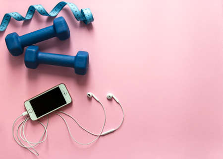 on a pink background dumbbells blue and flying centimeter figure sport headphones music phone iphone smartphone soft lightの写真素材