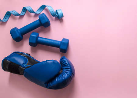 on a pink background dumbbells blue and flying centimeter figure sport boxing glove soft lightの写真素材