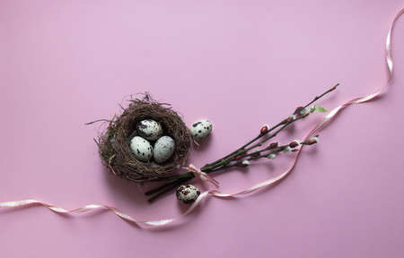 on a pink background, willow branches blossomed leaf green eggs quail nest with three eggs color view from above ribbon bow pinkの写真素材