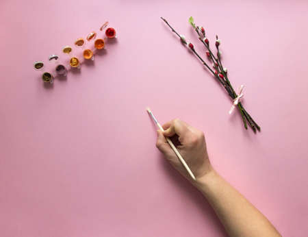 on a pink background of a paint of red and orange color with a brush hand paints draws near a branch of a pussy-willow a ribbon has blossomed a leafの写真素材