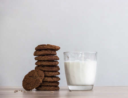 on a wooden table on a white background stands a stack of oatmeal cookies sunflower seeds a glass of milkの写真素材
